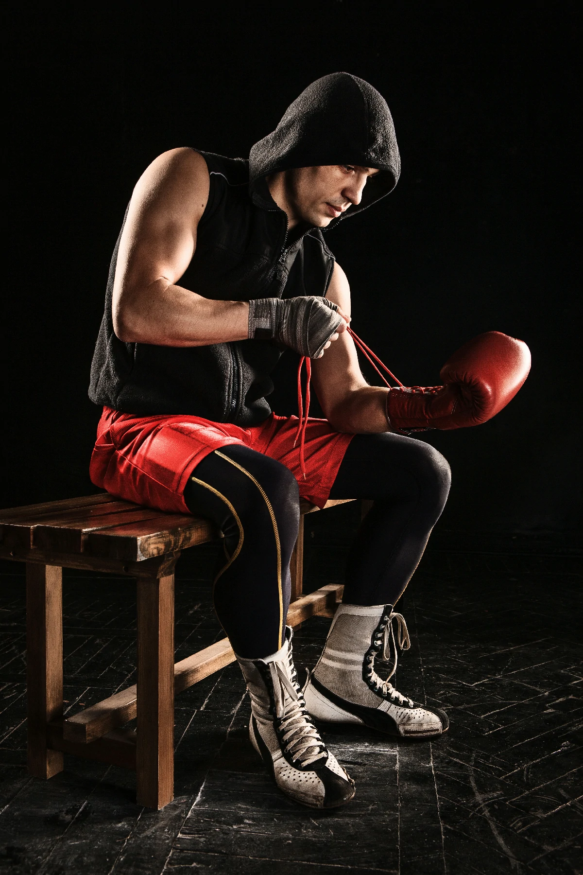 young male athlete kickboxing sitting lacing glove black